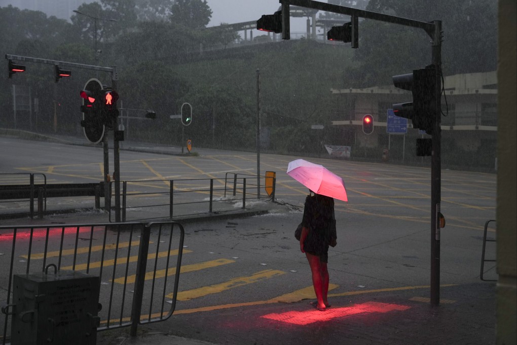 A woman waits to cross a flooded section of New Clear Water Bay Road in Choi Hung on August 5. The Hong Kong Observatory had issued a black rainstorm warning for the second time in six hours. Photo: Sam Tsang