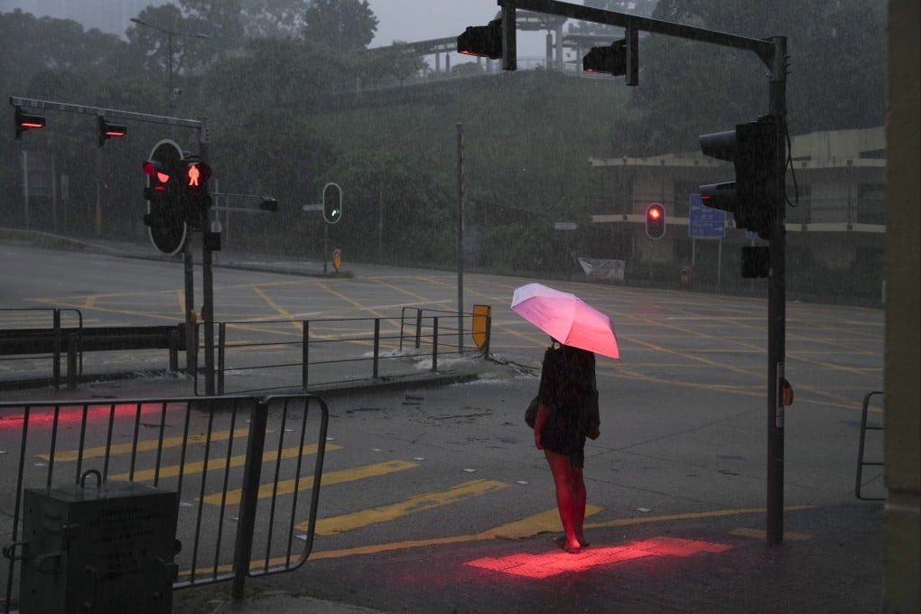A woman waits to cross a flooded section of New Clear Water Bay Road in Choi Hung on August 5. The Hong Kong Observatory had issued a black rainstorm warning for the second time in six hours. Photo: Sam Tsang