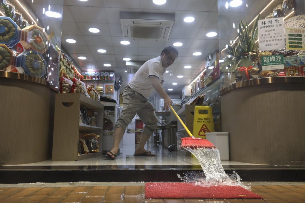 Shop staff in Sai Ying Pun clean up flood water during the black rainstorm on August 5, 2025. Photo: Karma Lo