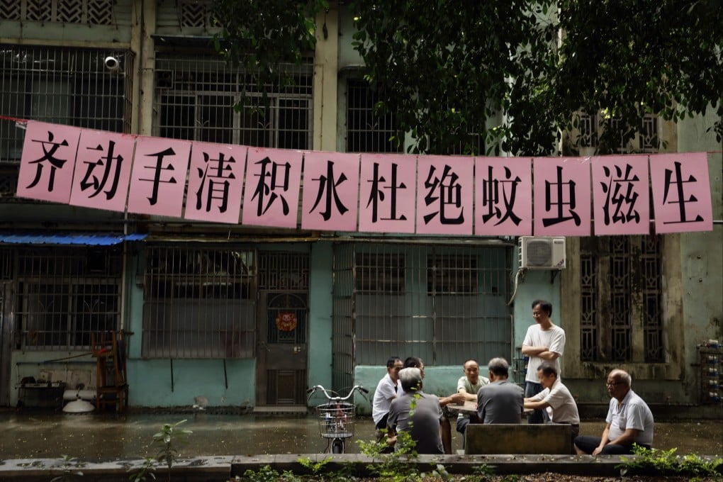 Residents play cards under a banner urging mosquito control at a residential compound, in Guangzhou, south China’s Guangdong province, on Wednesday. The slogan reads: “Let’s work together to clear stagnant water and eliminate mosquito breeding”. Photo: Chinatopix via AP