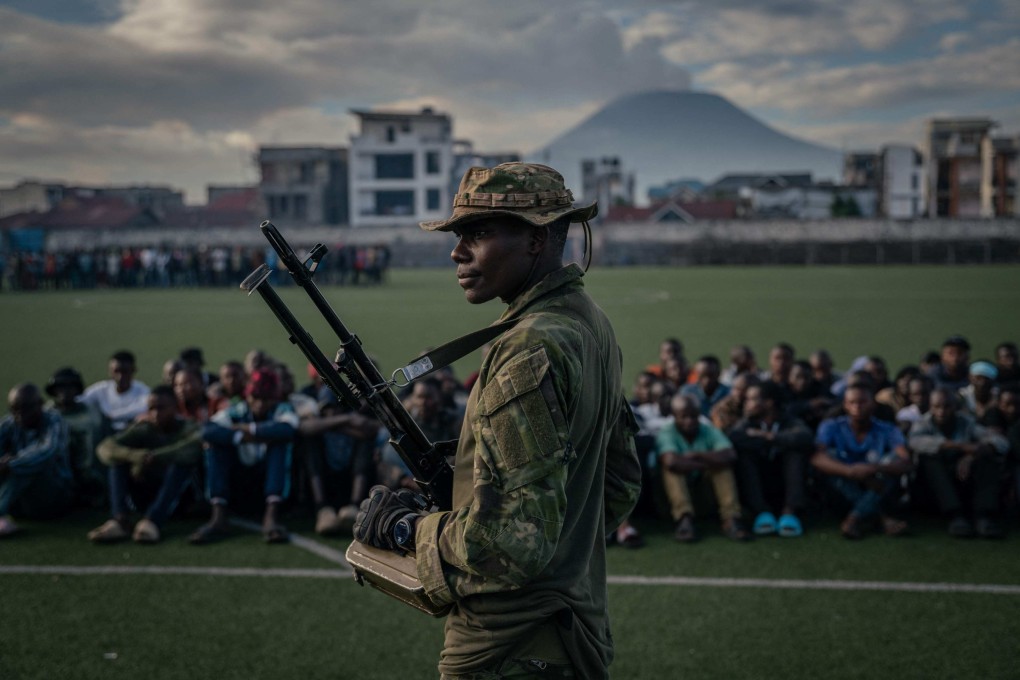 An M23 soldier watches over a group of around one hundred Democratic Forces for the Liberation of Rwanda (FDLR), Wazalendo and Armed Forces of the Democratic Republic of the Congo (FARDC) fighters, at the Stade de l’Unité, in Goma, DR Congo, on May 10. Photo: AFP
