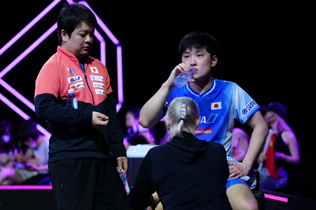 Tomokazu Harimoto (right) being tended to during a medical timeout in the final against Wang Chuqin on Monday. Photo: Xinhua