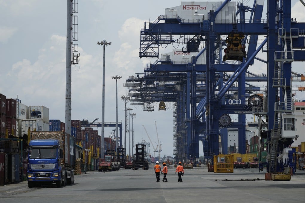 Workers walk beside stacks of containers at a port in Manila on Thursday. Exporters in the Philippines are bracing for the “devastating” consequences of a possible 100% tariff on semiconductors. Photo: AP