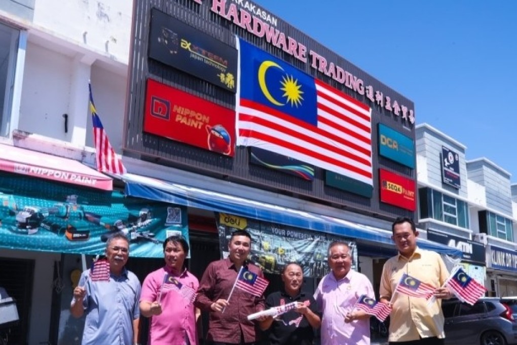 DAP members install a giant Malaysian flag on Wednesday outside a hardware store in Penang that recently went viral for flying the flag upside down. Photo: X/GenZMalaysia