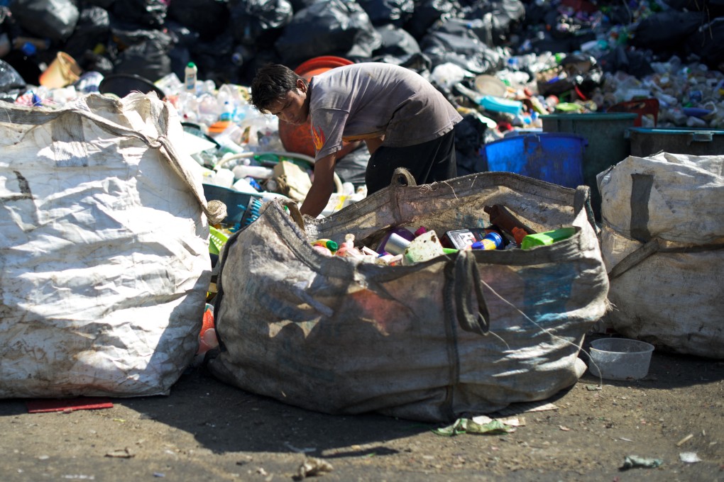 A worker gathers plastic waste to recycle in Ampang, Malaysia. Based on current trends, the world’s fossil‑fuel‑based plastic output will nearly triple by 2060 and plastic waste will exceed 1 billion tonnes. Photo: AFP