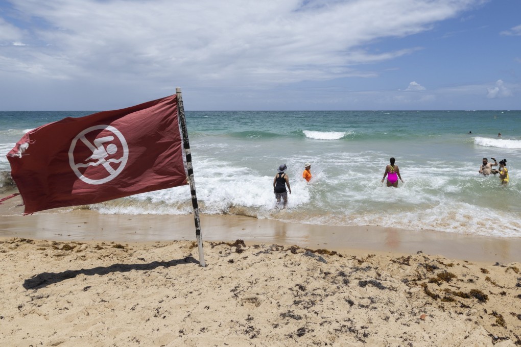 People disregard a warning flag on the beach in Condado, Puerto Rico, on Friday as Hurricane Erin approaches. Photo: AP