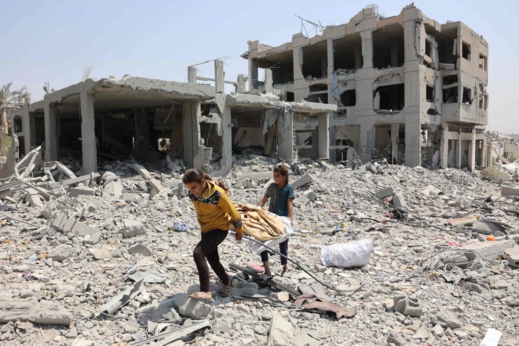 Palestinian girls carry salvaged items across the rubble in Gaza City on Thursday. Photo: AFP