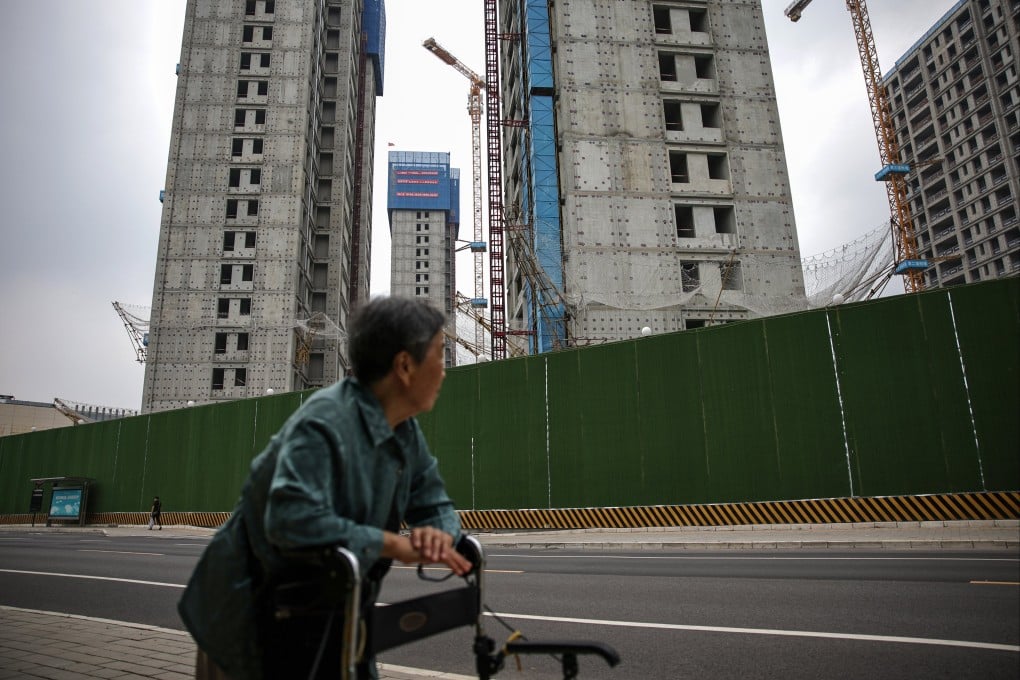 A woman walks past buildings under construction in Beijing, where the local government has eased rules to spur home purchases. Photo: EPA