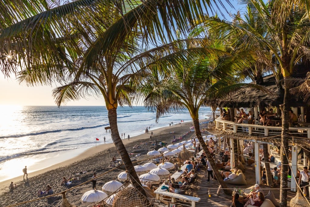 View of a beach restaurant terrace, crowded with tourists at the famous Echo Beach at sunset. Photo: Shutterstock
