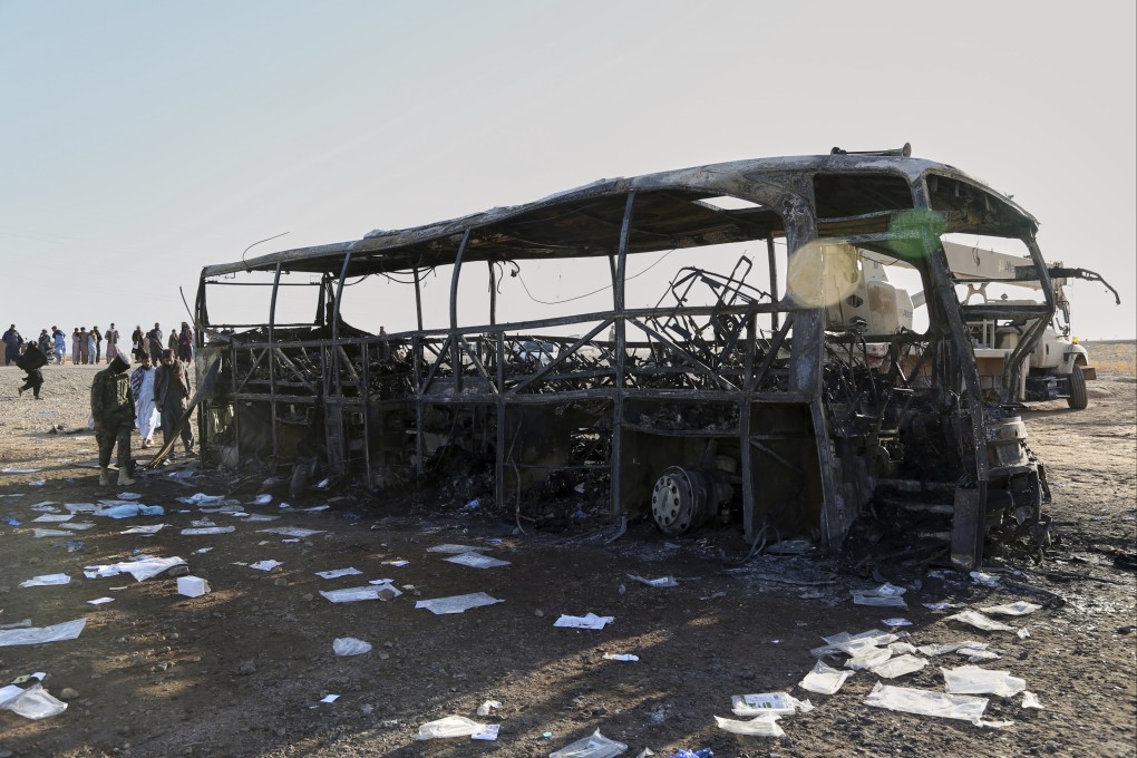 People and soldiers from the Taliban army inspect a burned-out bus that collided with a truck and a motorbike on Tuesday evening. Photo: AP