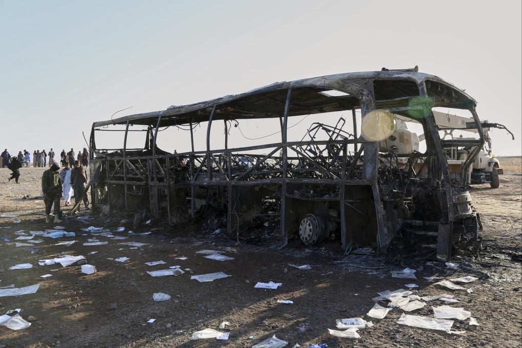 People and soldiers from the Taliban army inspect a burned-out bus that collided with a truck and a motorbike on Tuesday evening. Photo: AP