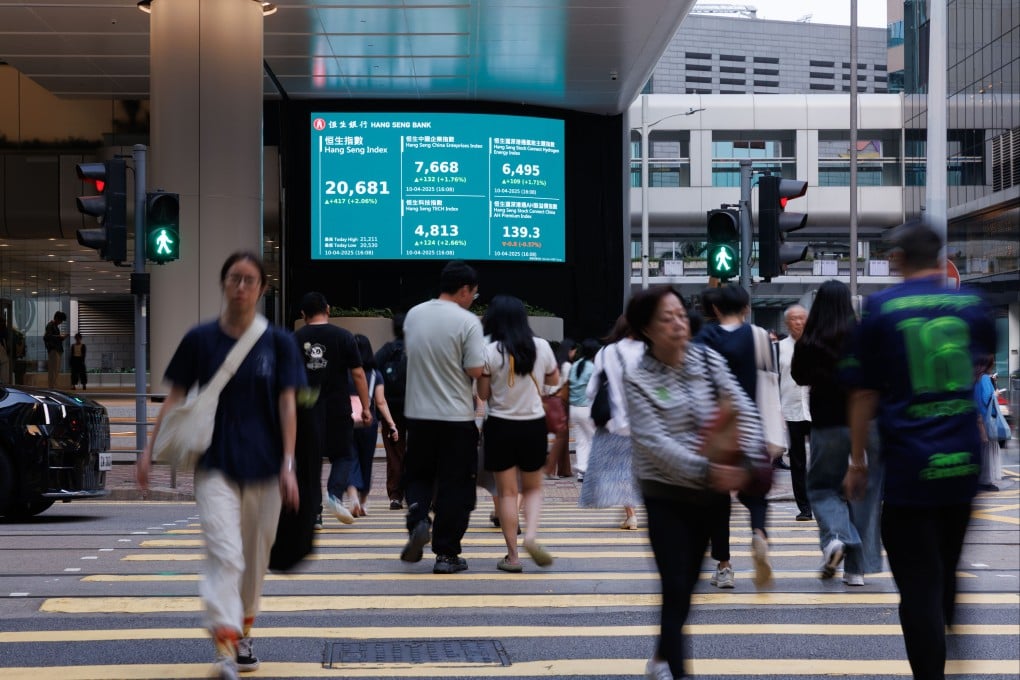 People walk past an electronic board showing the Hang Seng Index in Hong Kong. Photo: Zuma Press Wire/dpa