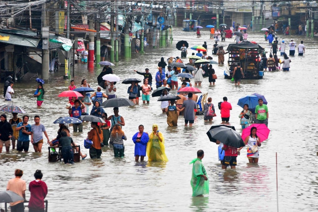Residents wade through a flooded street after heavy rains in Dagupan City, north of Manila, last month. Photo: AFP