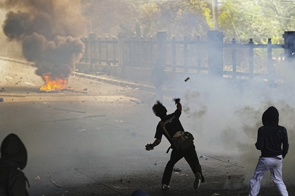 A student throws a rock towards riot police during a protest in Jakarta, Indonesia on Monday. Photo: AP