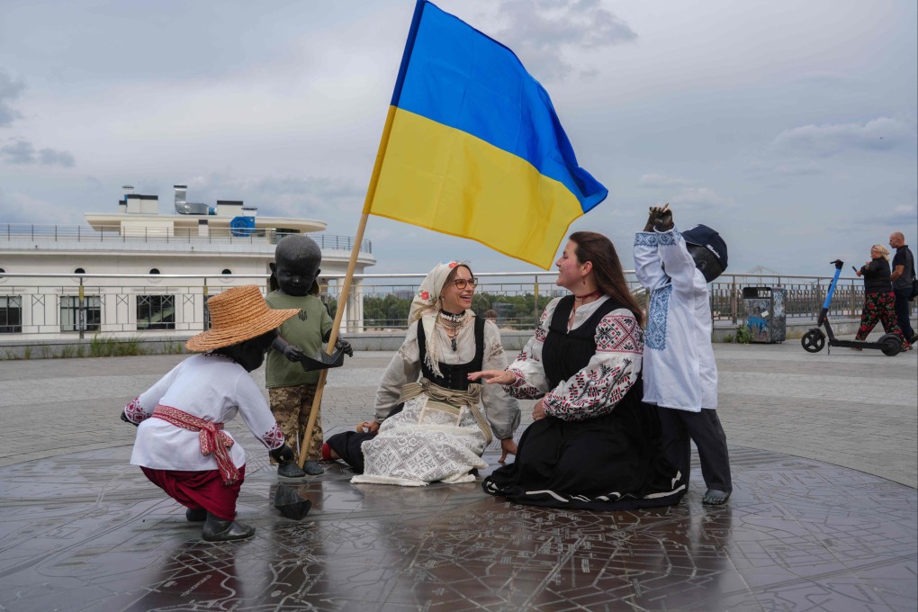 Girls in traditional Ukrainian outfits sit near the monument “Children Launching Paper Boats” in Kyiv on Ukraine’s independence day on Sunday. Photo: AFP