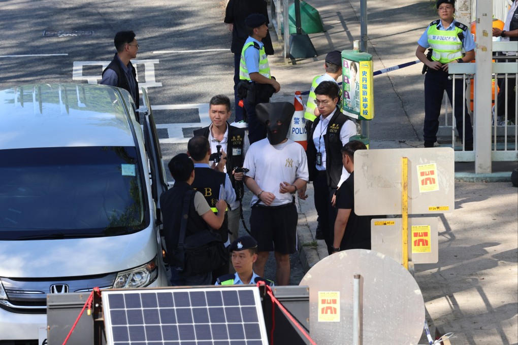 The hooded suspect is escorted back to Pik Uk Prison for a crime scene reconstruction. Photo: Jelly Tse