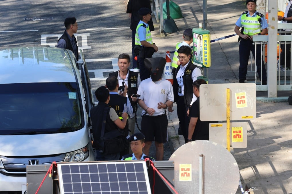 The hooded suspect is escorted back to Pik Uk Prison for a crime scene reconstruction. Photo: Jelly Tse