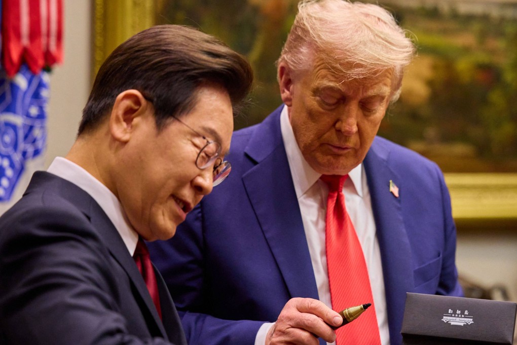 US President Donald Trump (right) looks at a handcrafted wood pen as South Korean President Lee Jae Myung signs a guest book before entering the Oval Office on Monday. Photo: Yonhap/AFP