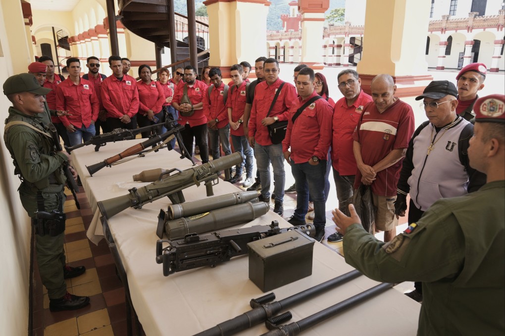 A member of the presidential guard shows weapons to people who signed up to join the civil militias during a national enlistment campaign in Caracas, Venezuela, on August 23. Photo: AP