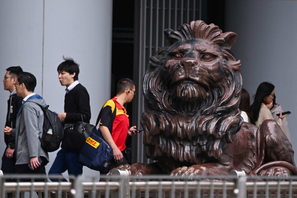 People walk past one of two bronze lions outside the HSBC building in Hong Kong on February 19, 2025. The finance sector, academia and the government need to work together to create a skilled talent pool that meets the city’s needs. Photo: AFP