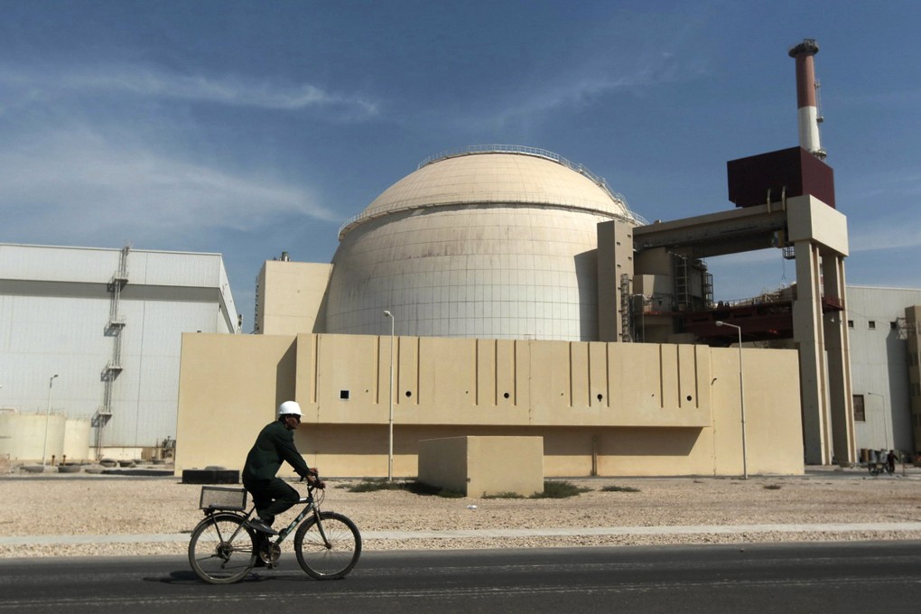 A worker rides a bicycle in front of the reactor building of the Bushehr nuclear power plant in Iran. Photo: AP