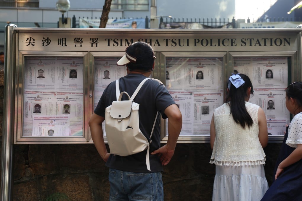 Passers-by look at a wanted notice posted outside Tsim Sha Tsui police station. Photo: Jelly Tse