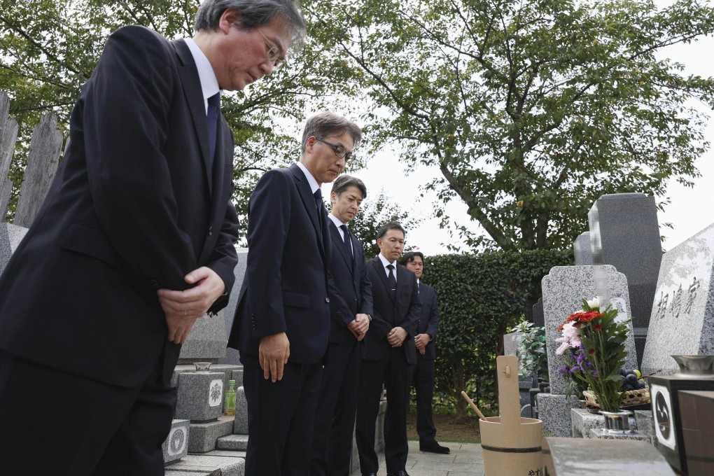 Japanese police officials and prosecutors bow their heads at the grave of Shizuo Aishima in Yokohama on Monday. Photo: AFP