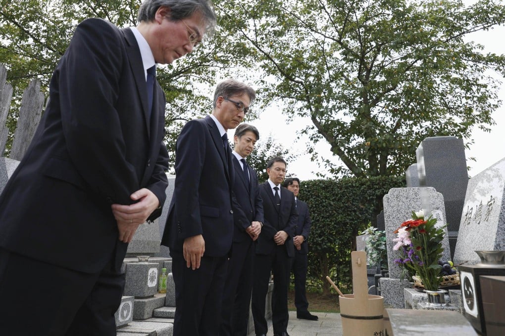 Japanese police officials and prosecutors bow their heads at the grave of Shizuo Aishima in Yokohama on Monday. Photo: AFP