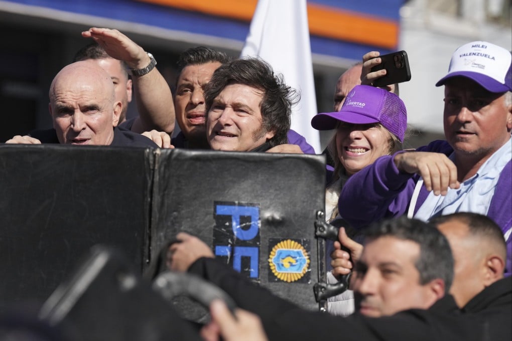 Police shield Argentine President Javier Milei and his sister, Secretary General of the Presidency Karina Milei, from objects thrown at them during a campaign rally in Lomas de Zamora on Wednesday. Photo: AP