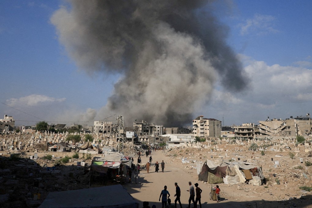 Palestinians gather near a cemetery as smoke rises following an explosion during an Israeli operation in Gaza City on Thursday. Photo: Reuters