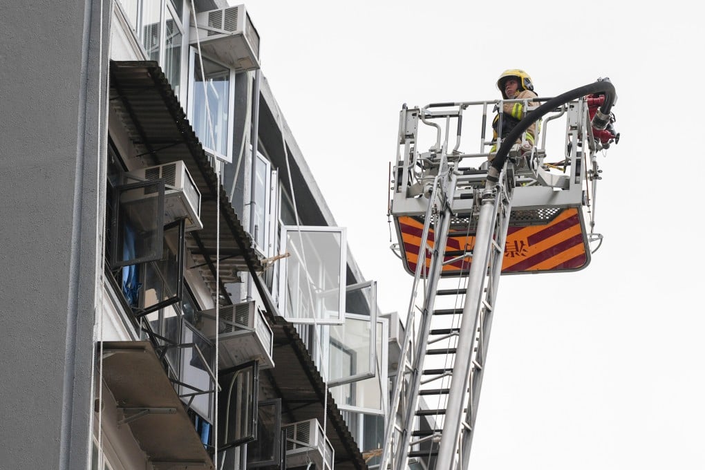Firefighters use a ladder to assess the Mido Apartments after a fire broke out at the building on King’s Road in North Point on August 23. Photo: Eugene Lee