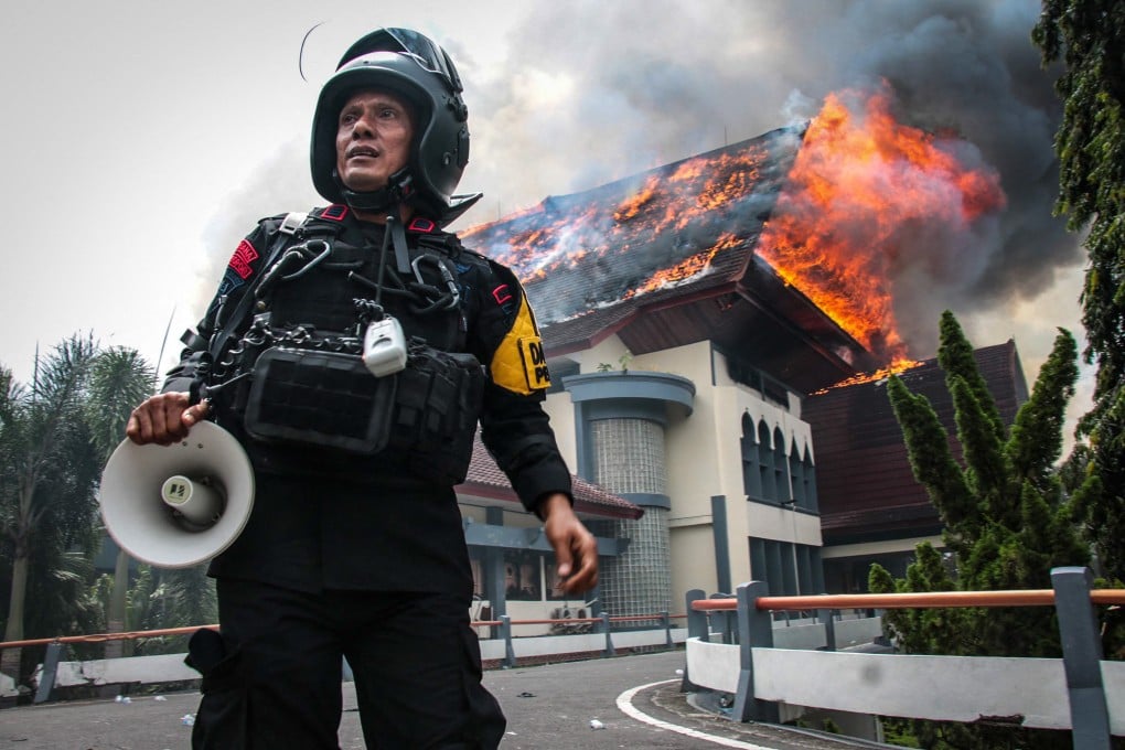 A police officer tries to restore order after protesters torch the West Nusa Tenggara Provincial Council building in Mataram on Lombok Island, West Nusa Tenggara, on Saturday. Photo: AFP