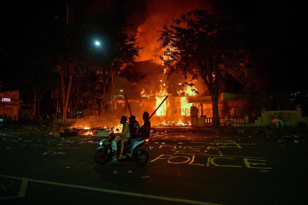 Indonesian protesters ride a motorcycle in front of a police headquarters that was burned and looted during demonstrations in Surabaya on Sunday. Photo: AFP