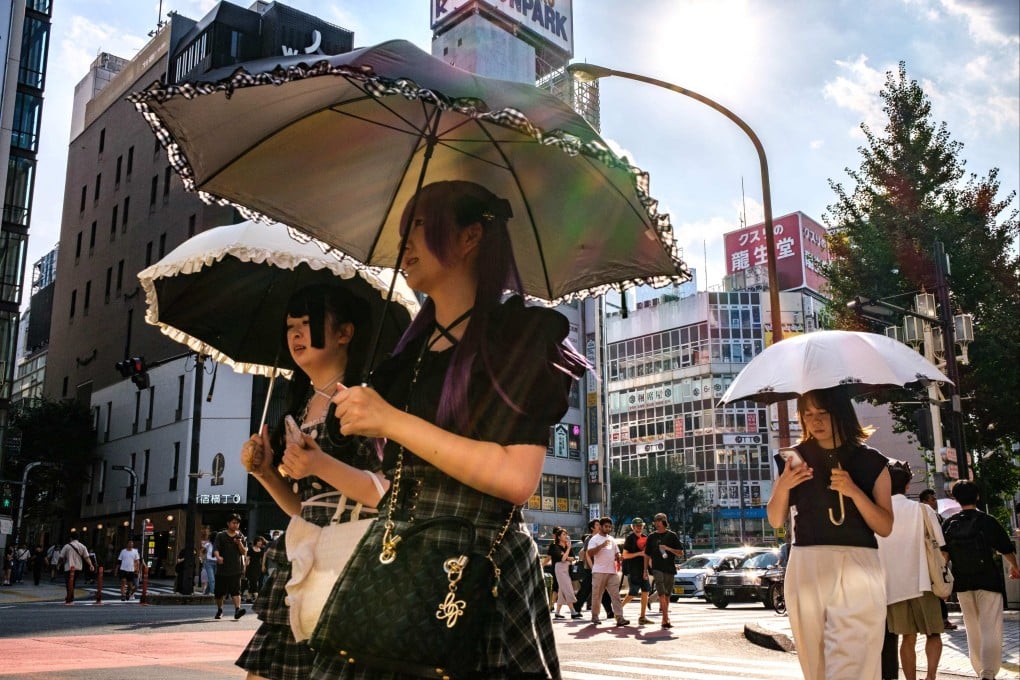 Pedestrians holding umbrellas walk on a hot day amid a heatwave in Tokyo’s Shinjuku district last month. Photo: AFP
