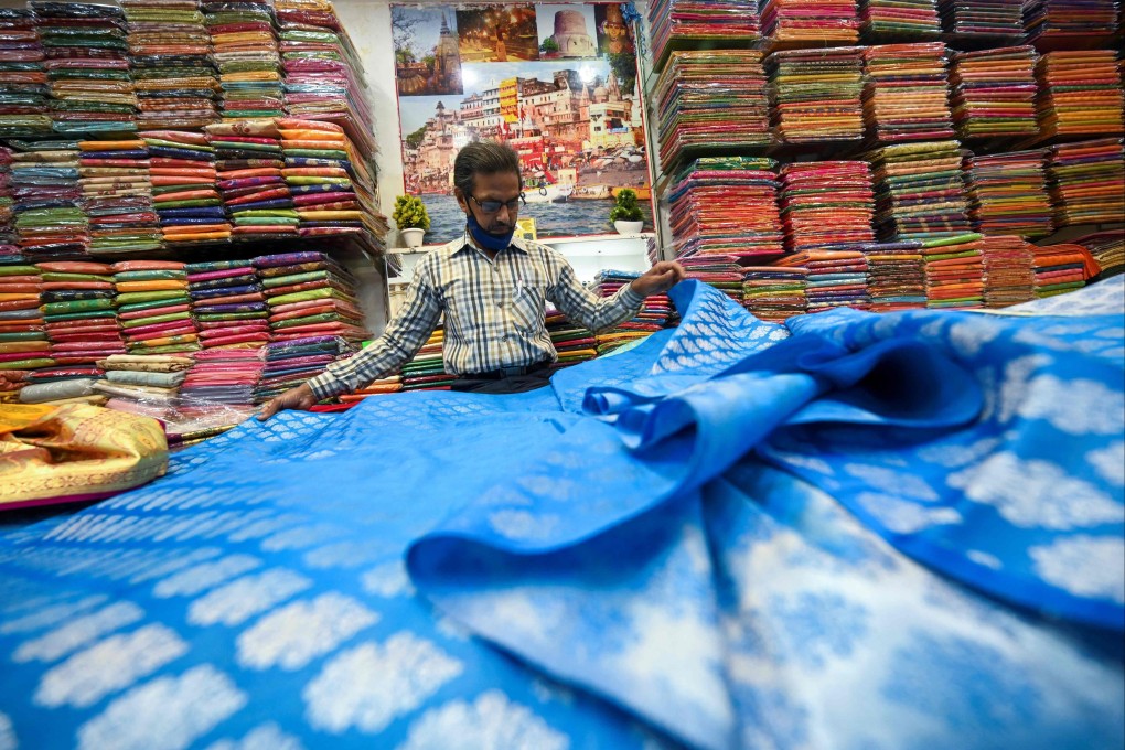 A shopkeeper shows a traditional Banarasi sari at a store in Varanasi on November 20, 2021. Photo: AFP