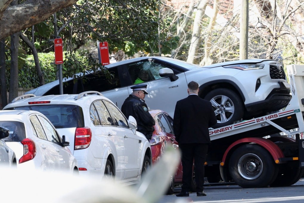 Police officers oversee the loading of a car that crashed into the Russian consulate in Sydney on Monday onto a tow truck. Photo: Reuters