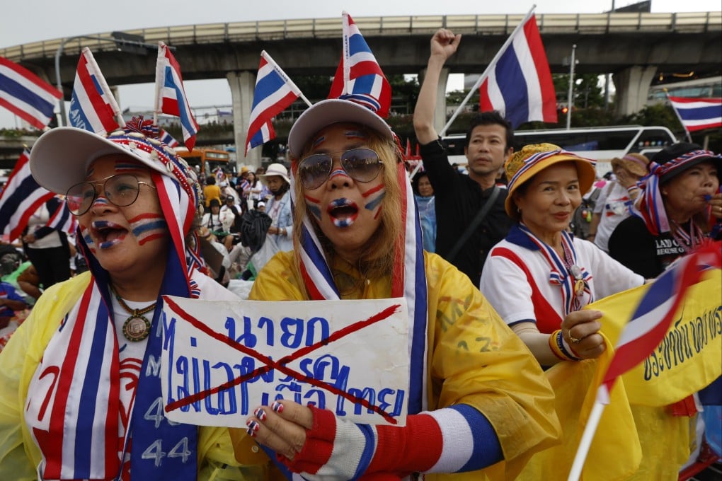 Demonstrators wearing accessories and face paint in the colours of Thailand’s national flag hold a sign reading ‘No prime minister from the Pheu Thai Party’ during a protest in Bangkok on Sunday. Photo: EPA