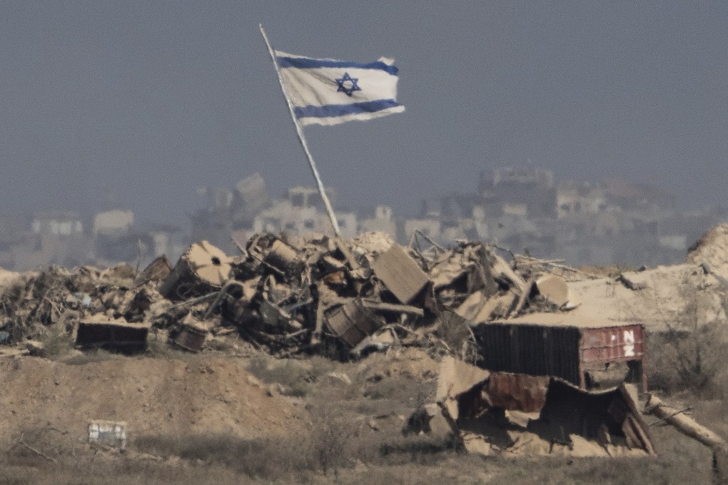 An Israeli flag waves over debris in an area of the Gaza Strip, as seen from southern Israel. Photo: AP