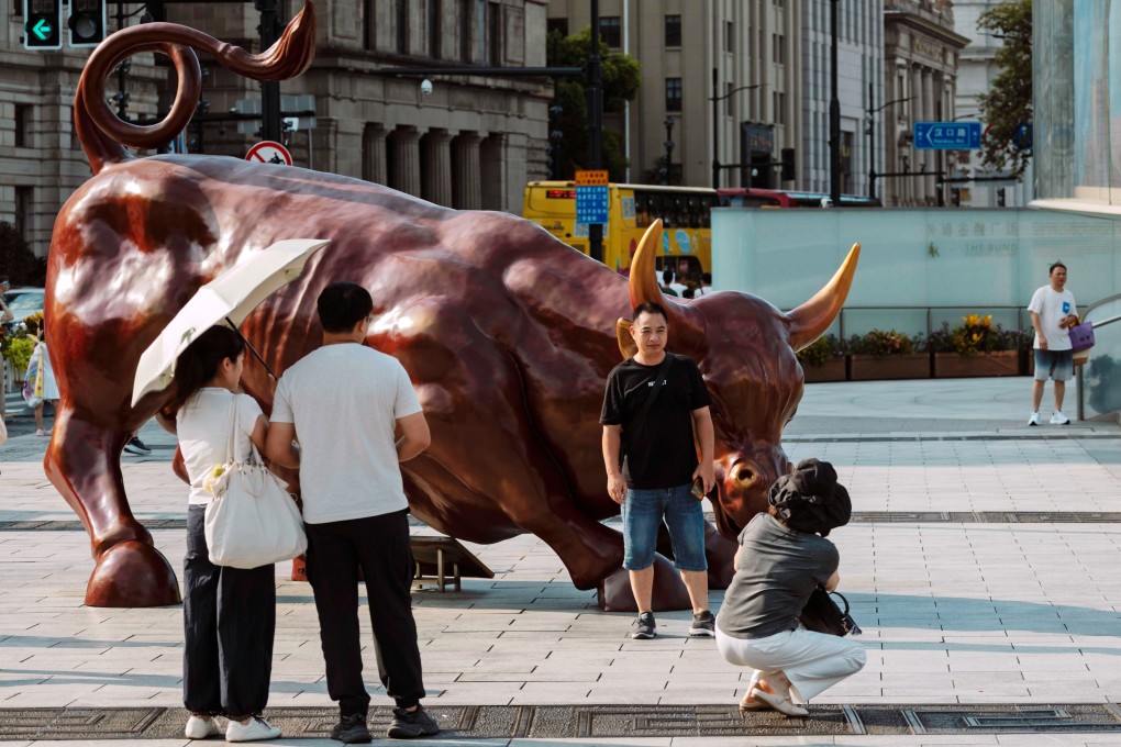 People pose near a bull statue in Shanghai on August 7, 2025. Photo: EPA
