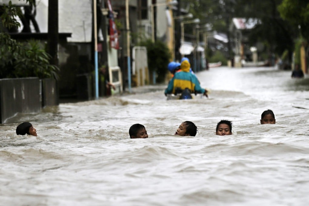 Young Filipinos make their way through floodwaters in the town of Hermosa, Bataan province. Photo: EPA