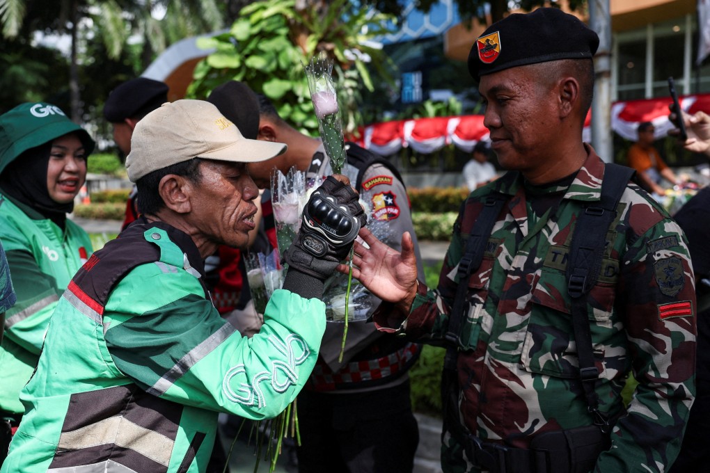 A ride-hailing motorbike rider gives a flower to a member of military personnel on Tuesday during a rally in Jakarta calling for peace following Indonesia’s widespread anti-government protests. Photo: Reuters