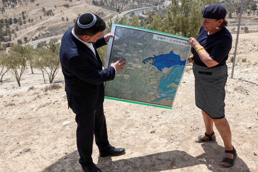 Israeli Finance Minister Bezalel Smotrich and a woman hold a map that shows the long-frozen E1 settlement scheme, that would split East Jerusalem from the occupied West Bank. Photo: Reuters