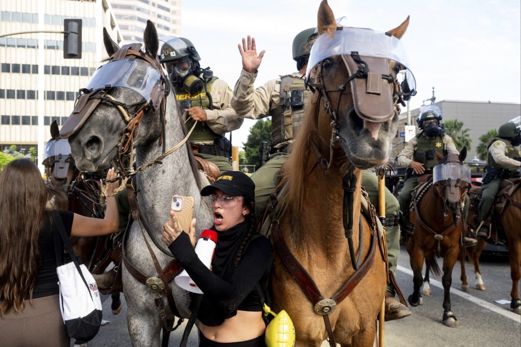 A demonstrator holds a phone in front of Los Angeles County Sheriffs on horseback during a protest on June 14 in Los Angeles, US. Photo: AP
