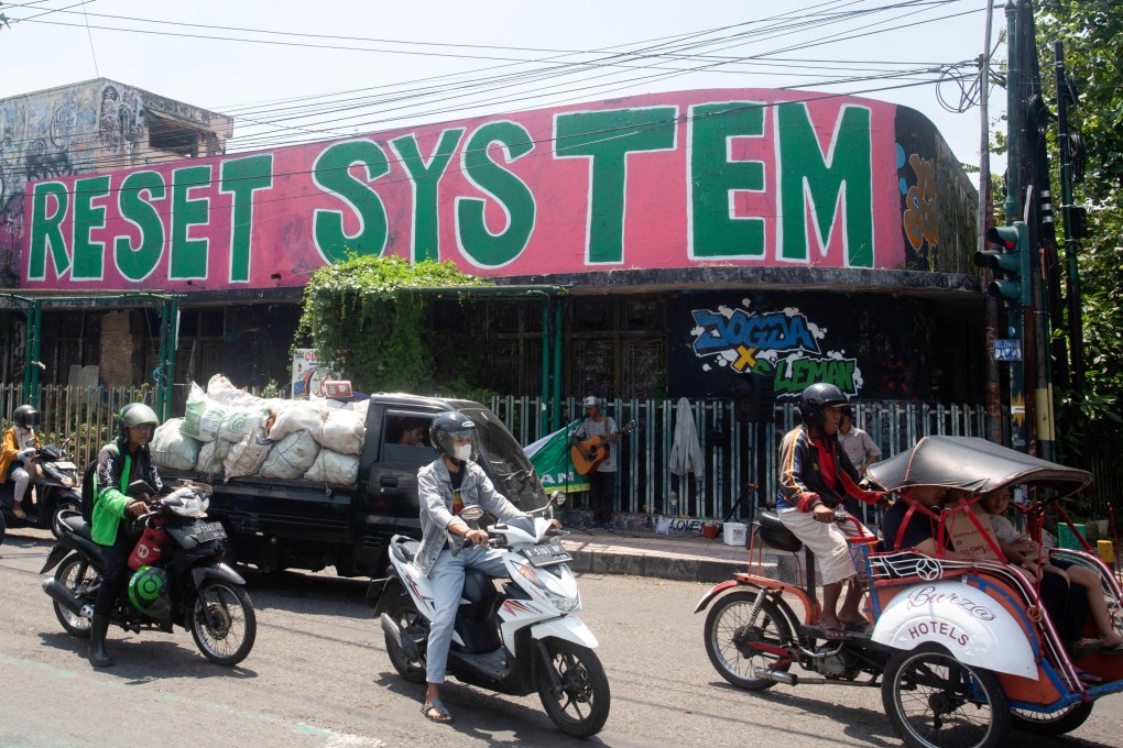 Graffiti that reads “RESET SYSTEM” is seen past traffic in Yogyakarta, Indonesia, on Wednesday. Photo: AFP