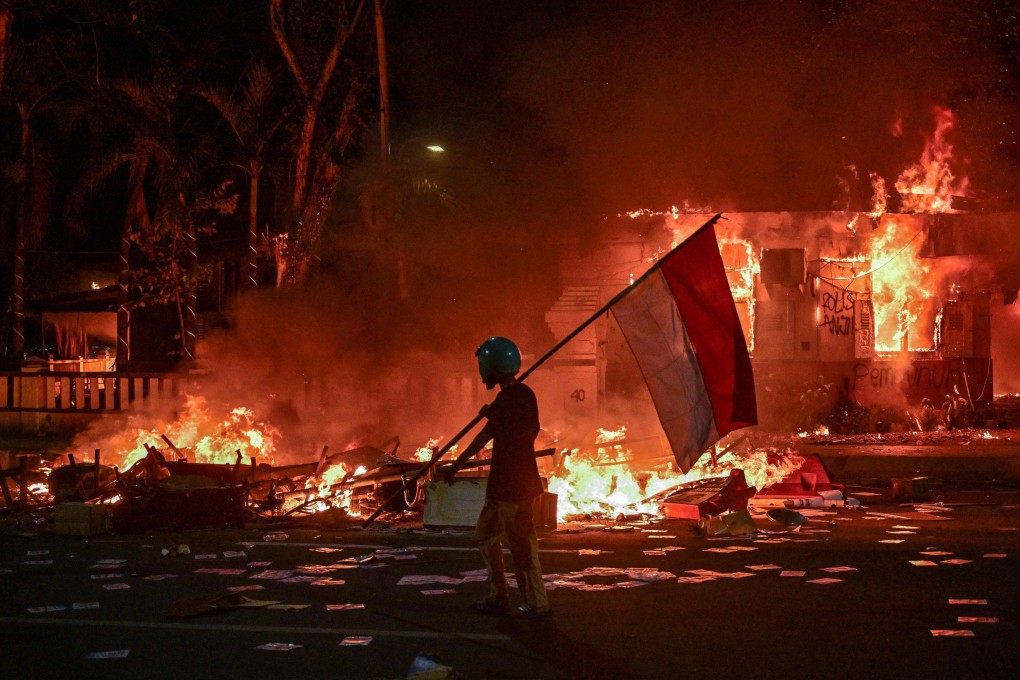 A protester walks with an Indonesian flag in front of a police headquarters that was set on fire in Surabaya on August 31. Photo: AFP