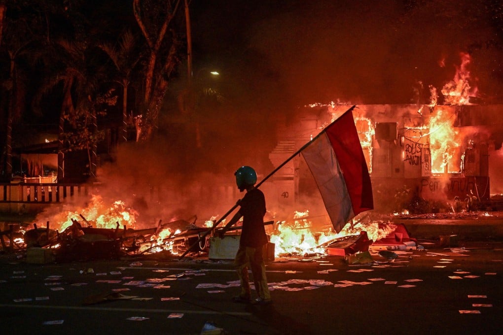 A protester walks with an Indonesian flag in front of a police headquarters that was set on fire in Surabaya on August 31. Photo: AFP