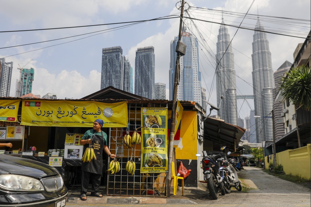 A man displays bananas outside his shop with the Malaysia’s iconic Petronas Twin Tower in the background in Kuala Lumpur in February 2024. Photo: EPA-EFE