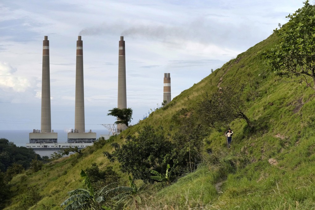 A couple walk on a hill called “Teletubbies Hill”, a locally popular tourist attraction, as the chimneys of Suralaya coal power plant loom in the background, in Cilegon, Indonesia, on January 8, 2023. Photo: AP