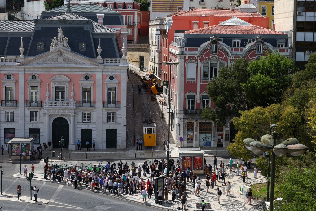 People gather at the base of the street on Thursday where a funicular crashed (top) in Lisbon, Portugal. Photo: Reuters