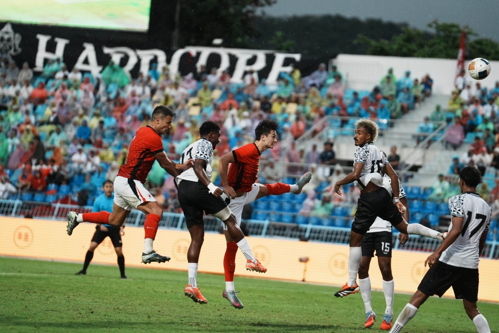 Hong Kong pair Dudu (left) and Matt Orr leap for a high ball in the Fiji penalty box. Photo: HKFA